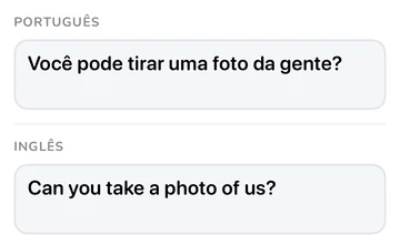Painel da frase com “Você pode tirar uma foto da gente?” em português e a tradução em inglês “Can you take a photo of us?”