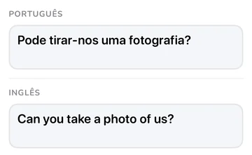 Painel da frase com «Pode tirar-nos uma fotografia?» em português e a tradução inglesa «Can you take a photo of us?»